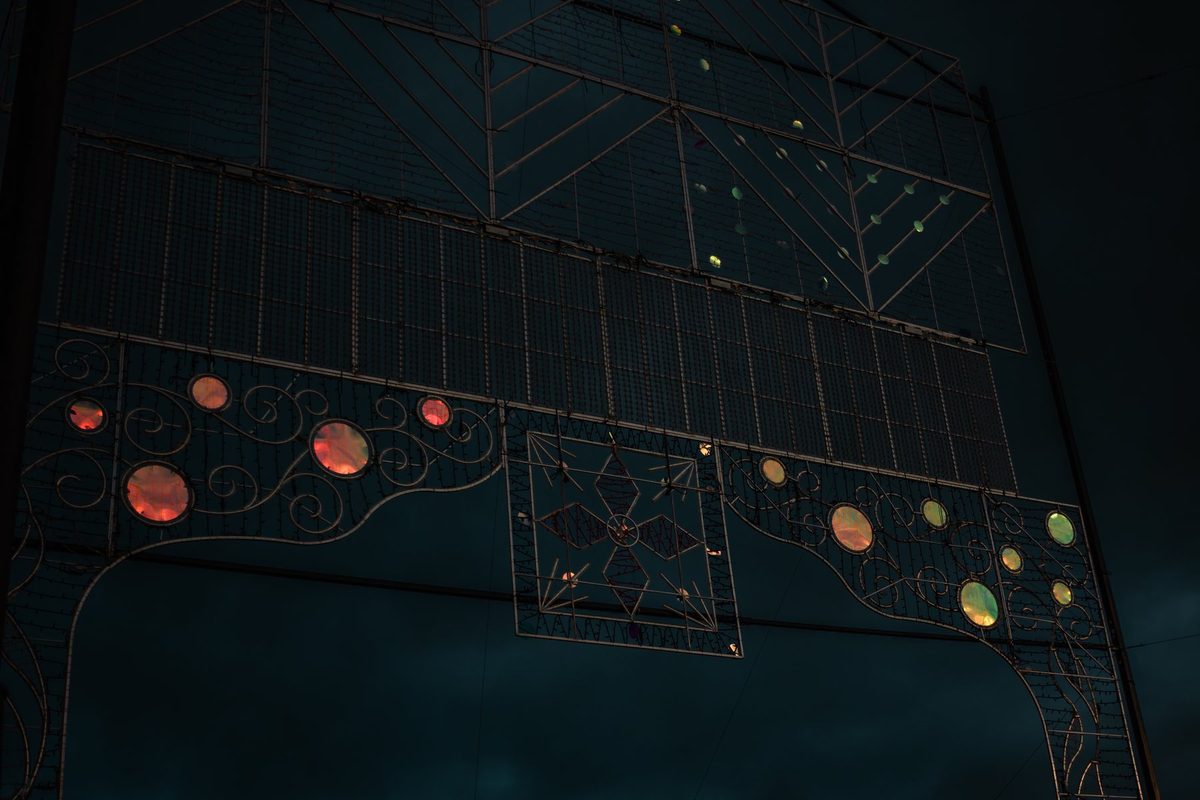 Un arco de luces de fiesta todavía apagado, con sus bombillas de colores contra el cielo azul oscuro.