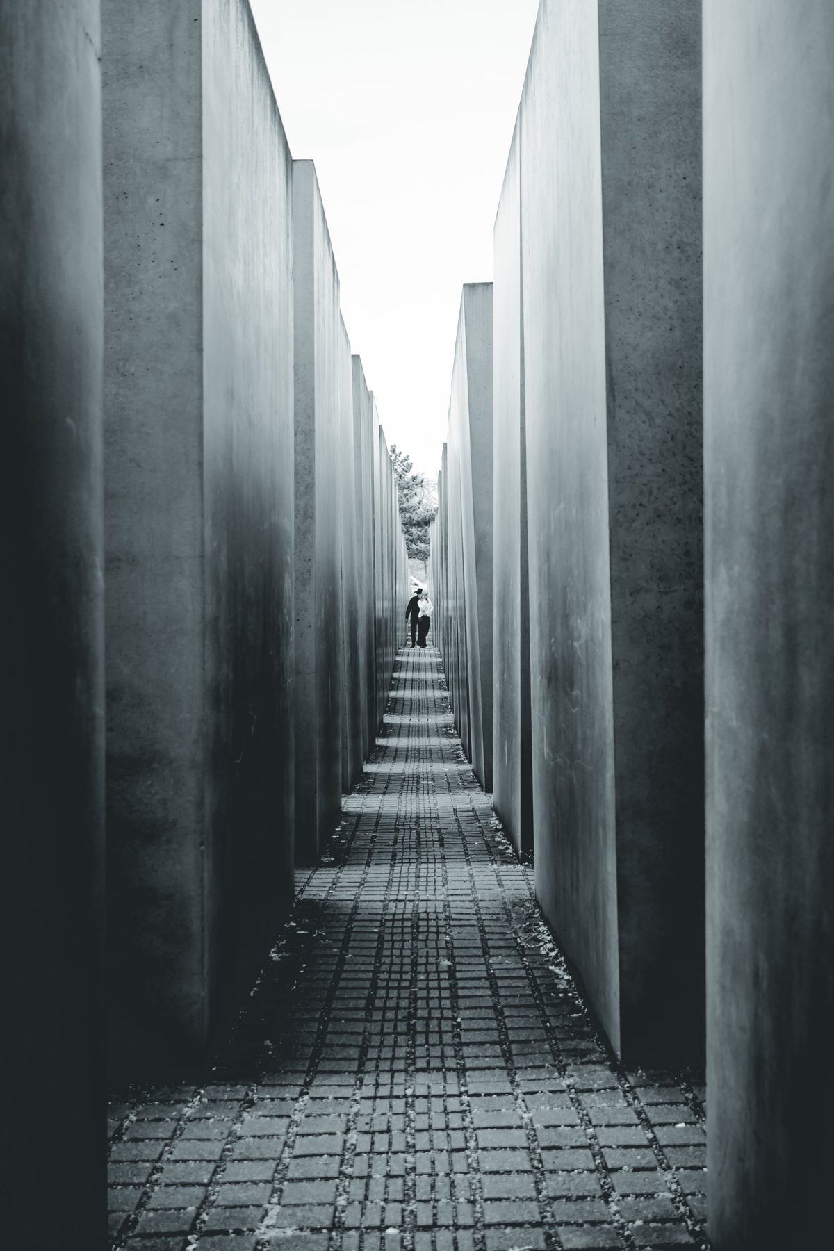 Un pasillo entre las estelas del Memorial. Al fondo, dos figuras diminutas dan la escala.
