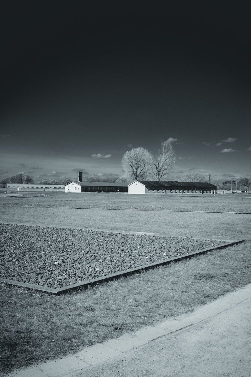 Gravel foundations in the foreground and the reconstructed barracks behind.