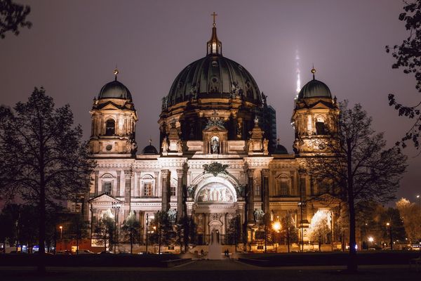 La catedral de Berlín iluminada en una noche de niebla, con la Torre de Televisión perdida en el cielo.