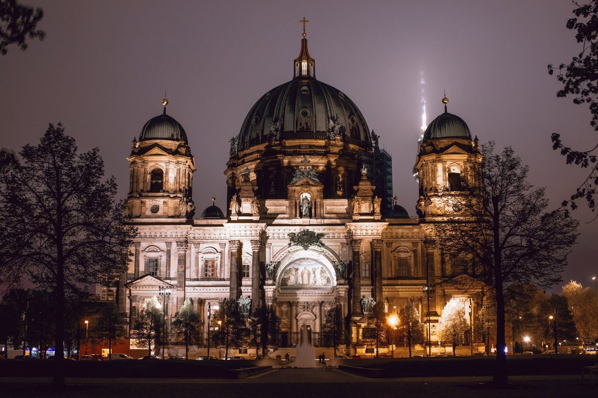 Berlin Cathedral lit up on a foggy night, with the TV Tower lost in the sky.