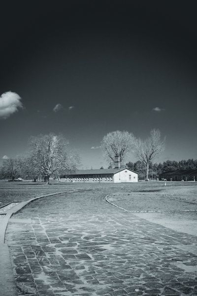 A path of irregular slabs crosses the former camp grounds towards one of the barracks.
