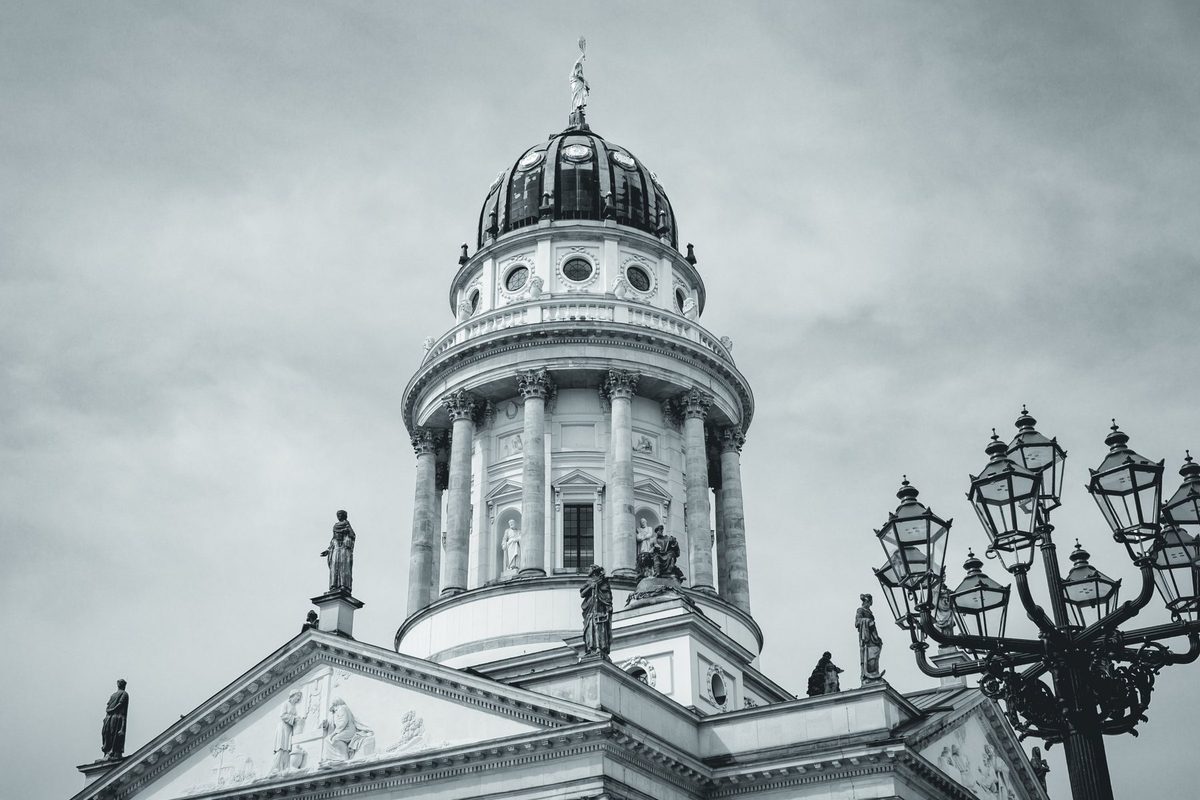 A historic Berlin street lamp keeps the dome company in a calm landscape frame.
