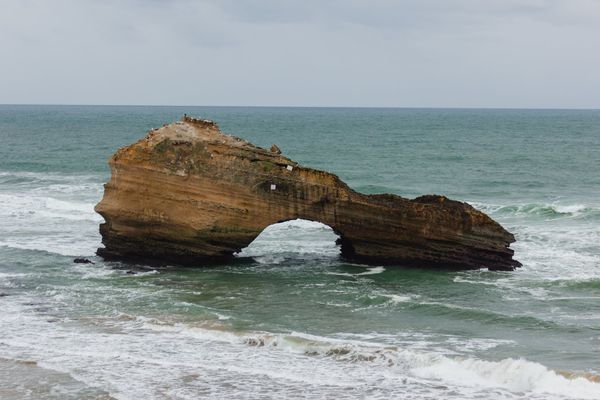 The sandstone rock and its arch, with Atlantic waves passing beneath.