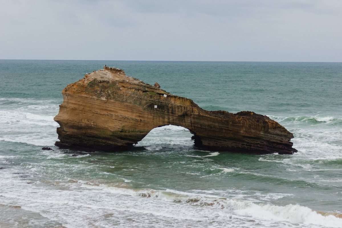 The sandstone rock and its arch, with Atlantic waves passing beneath.