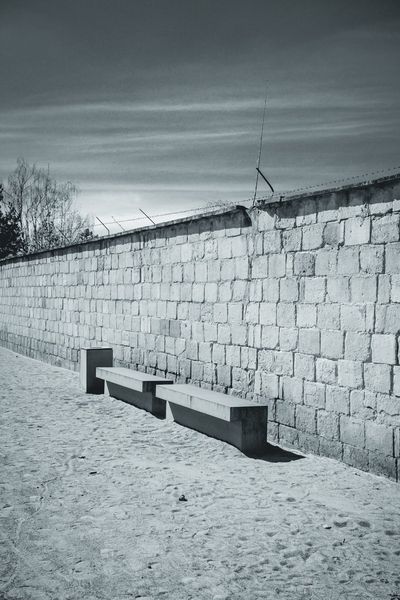 Two concrete benches at the foot of the camp wall, still topped with barbed wire.