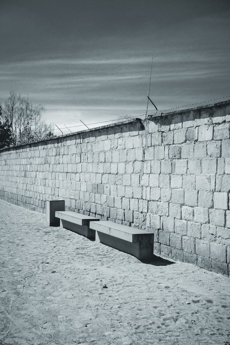 Two concrete benches at the foot of the camp wall, still topped with barbed wire.