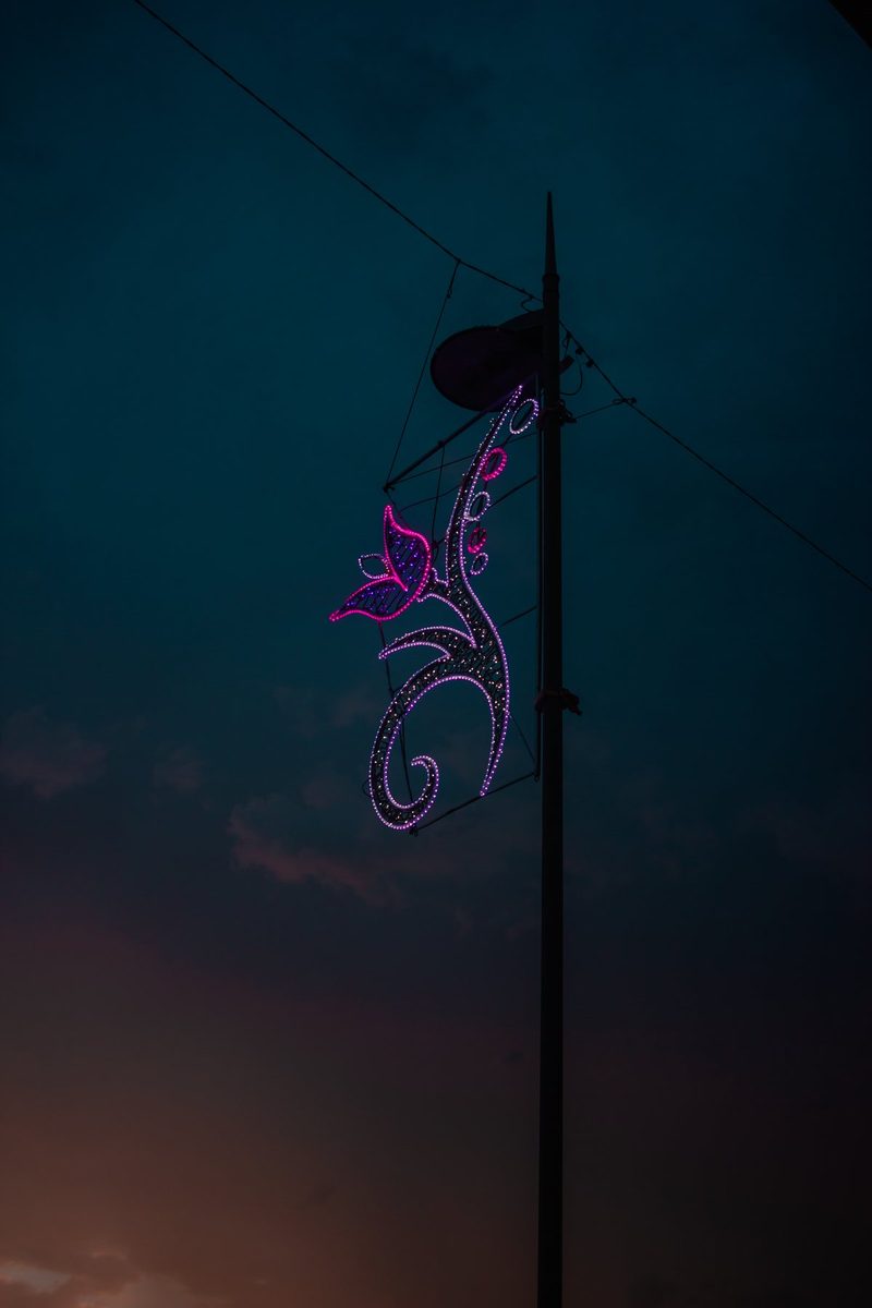 Una flor de luces violetas colgada de una farola, contra el cielo azul del anochecer.