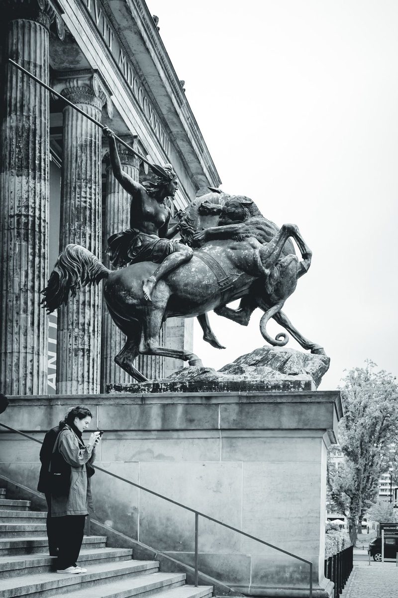 The bronze Amazon on horseback in front of the Altes Museum, and a visitor absorbed in her phone.