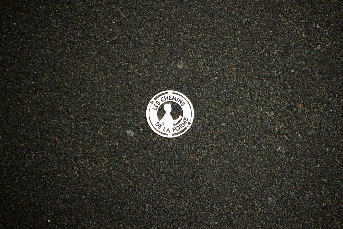 A metal plaque from the fitness trail set into the asphalt.
