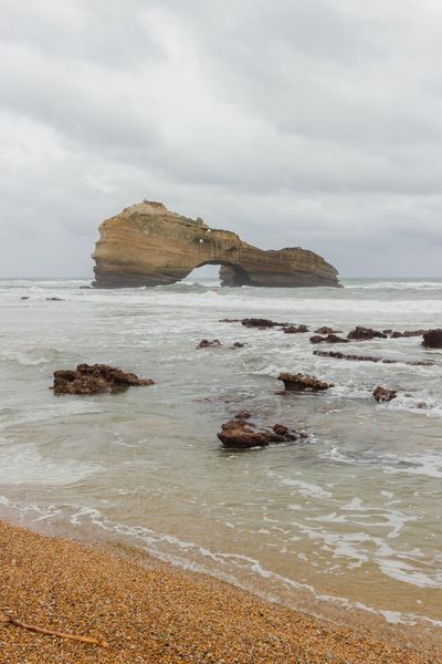 The same shore in colour: golden shingle, greenish water and the arch in the distance.