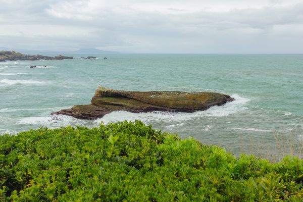 A flat rock surrounded by foam, seen from the lighthouse cliff.