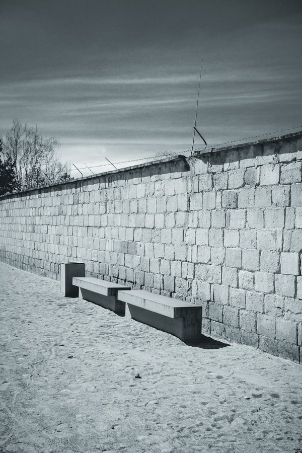 Dos bancos de hormigón al pie del muro del campo, todavía coronado de alambre de espino.