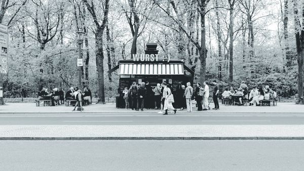 Un quiosco de salchichas bajo los árboles del Tiergarten, con su corrillo de clientes.